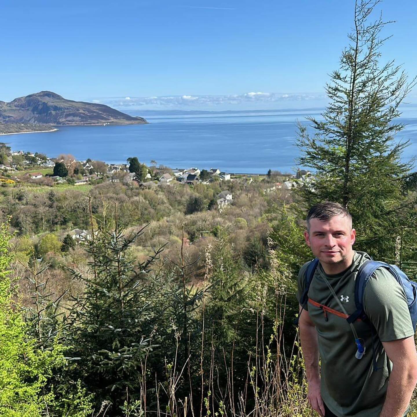 A runner with a backpack above the coastal village and bay.