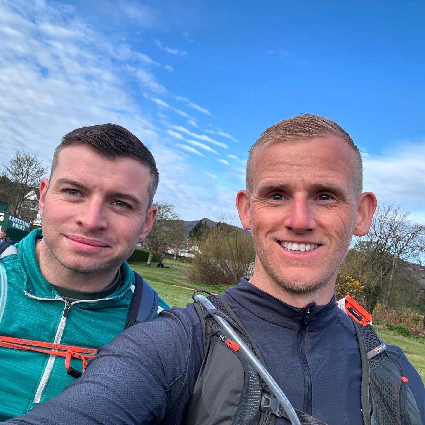 Two runners taking a selfie under a blue sky.