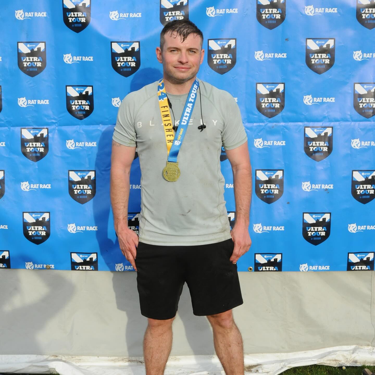 A second runner wearing a finisher medal at the Rat Race Ultra Tour backdrop.